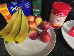 A plate with bananas, apples, and a box of Tetley tea bags. - Private & Charming Annex. Wi-Fi, Free parking, 15 min to Swindon Designer shops. (Highworth)