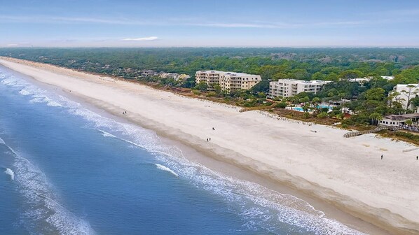 Un hotel costero con vista a la playa, varias edificaciones y una playa de arena.