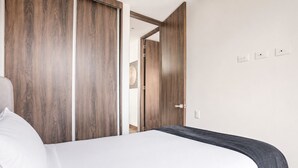 A hotel room with a bed, a wardrobe, and a door leading to another room. - 2-bedroom apartment in lovely Bogotá with fitness room access (Bogotá)