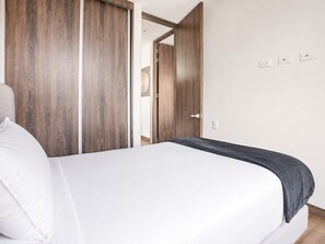 Ein Hotelzimmer mit einem Bett, einem Kleiderschrank und einer Tür zu einem weiteren Raum.