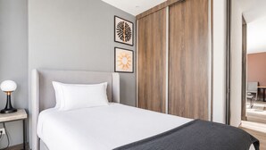 A modern hotel room with a large bed, a nightstand, and a wooden wardrobe. - 2-bedroom apartment in lovely Bogotá with fitness room access (Bogotá)