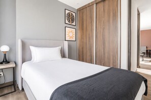 Ein modernes Hotelzimmer mit einem großen Bett, einem Nachttisch und einem Holzschrank.