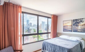 A hotel room with a large window, a bed, a chair, and two paintings on the wall. - Modern Studio 220 m From Farol Beach Bpm1309 (Salvador)