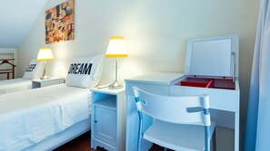 Ein Hotelzimmer mit zwei Betten, einem Schreibtisch mit Stuhl, einer Lampe, einem Schrank und einem Bild an der Wand.