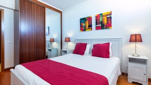 A hotel room with a large bed, two bedside tables, a nightstand, a wooden wardrobe, and two abstract paintings on the wall. - The Sea Terrace - Rooftop Beach Duplex - Centre (Portimão)