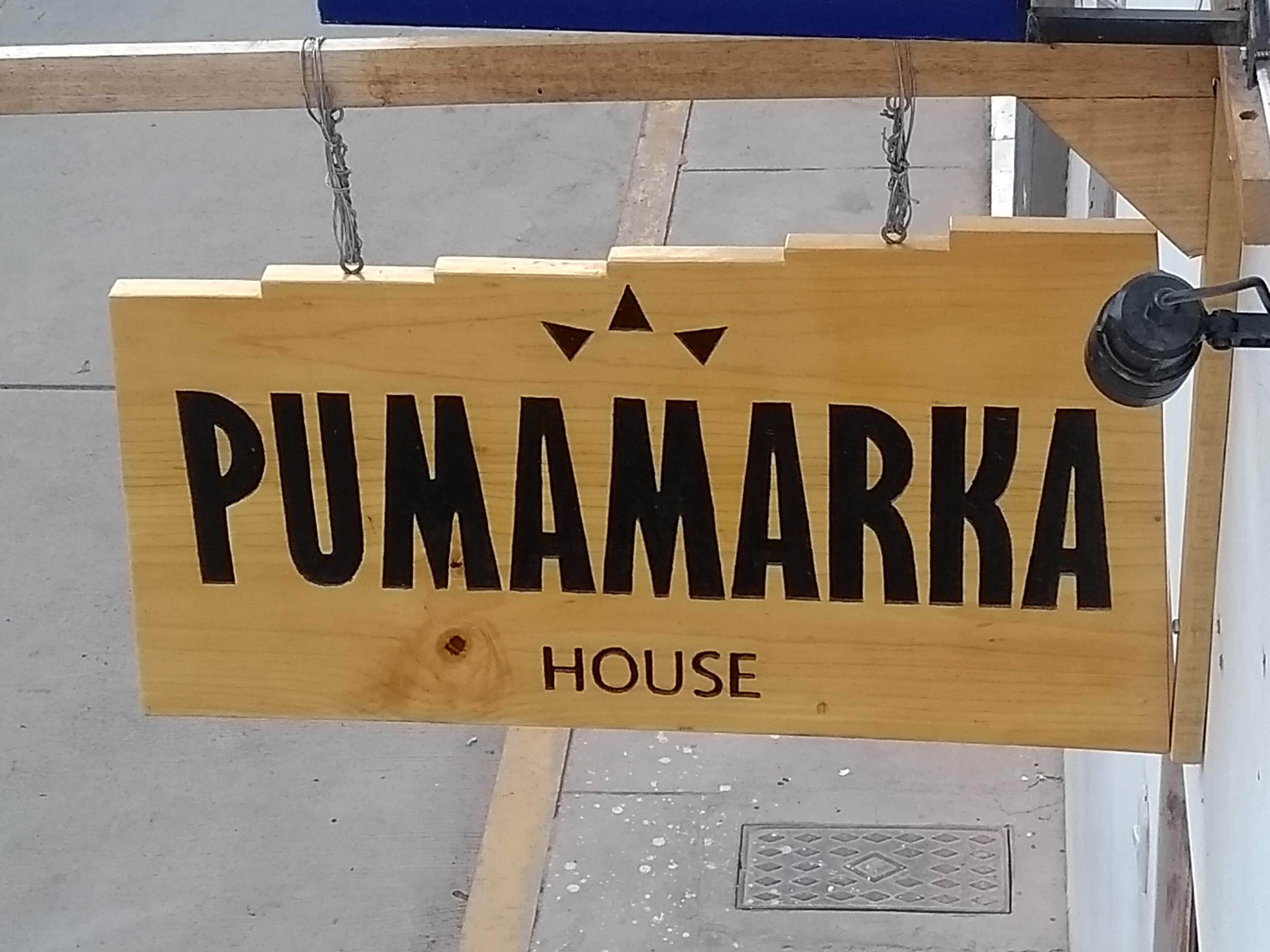 A wooden sign with the text 'PUMAMARKA HOUSE' indicating the name of a property.