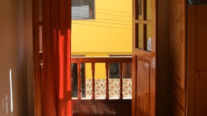 Une pièce avec un lit, une armoire en bois et une fenêtre avec des rideaux.