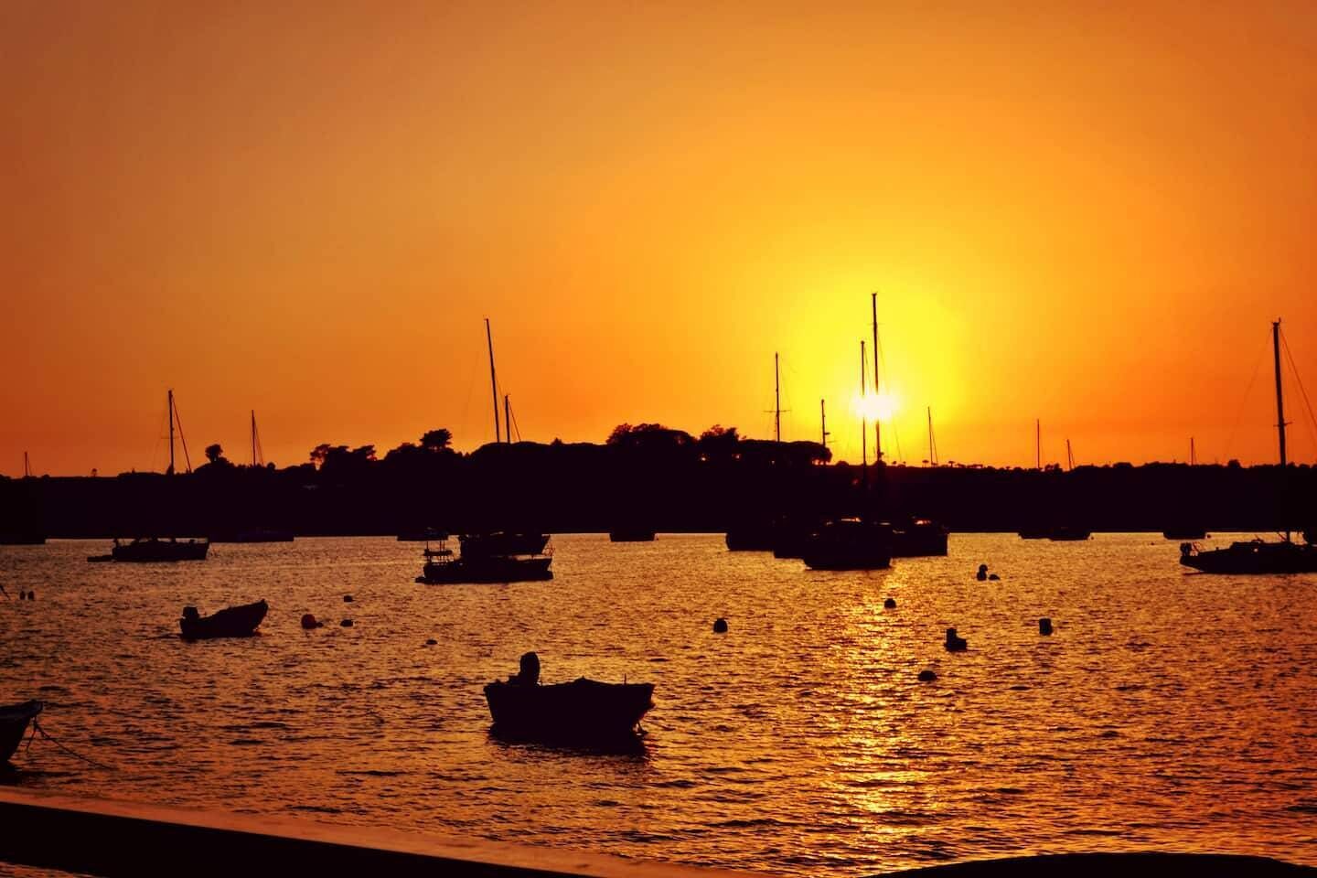 Ein Sonnenuntergang über einem Gewässer mit mehreren Booten.