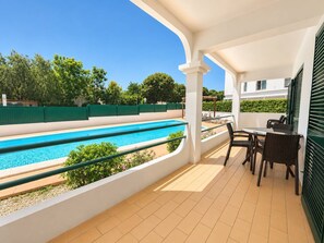 A poolside area with a clear view of a swimming pool, a table with chairs, and a covered patio. - The Sea Breeze - Bright Beach Apartment - Centre (Portimão)