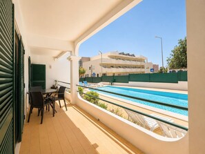 Un balcon avec une piscine, du mobilier d’extérieur et une vue sur un immeuble doté de balcons.