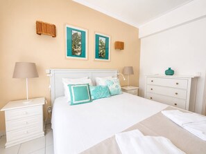 A bedroom with a bed, bedside tables, a dresser, and wall-mounted lamps. - The Sea Breeze - Bright Beach Apartment - Centre (Portimão)