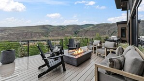 A deck with outdoor furniture, a fire pit, and a view of a valley. - EagleVail Designer Retreat | Sleeps 16 (Vail)
