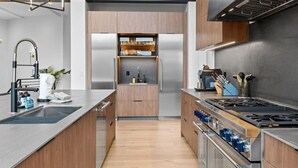 A modern kitchen with a central island, stainless steel appliances, and wooden cabinetry. - EagleVail Designer Retreat | Sleeps 16 (Vail)