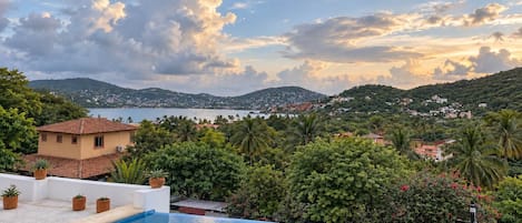 A pool with a view of a coastal town and hills.