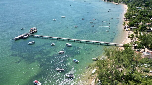 A coastal area with a pier extending into the sea, surrounded by boats and a beach with buildings and greenery. - House by Lagoon, Near Beach Cdl0007 (Maraú)