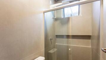 Un baño moderno con ducha envuelta en vidrio, inodoro y barra para toallas.