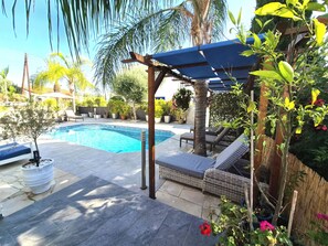 Ein Schwimmbecken mit Liegestühlen und einer Pergola.
