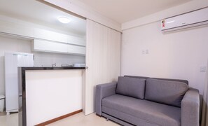A compact living space with a kitchenette, a grey sofa, and a white curtain. - Comfort in Marau: 200m From the Beach - Cpr0108 (Maraú)