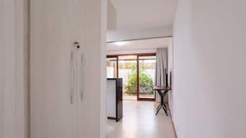 Un pasillo con una puerta corredera de vidrio que da a un área exterior con una mesa y sillas.