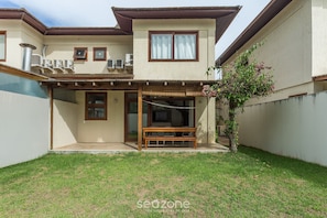 A two-story house with a covered patio, a wooden bench, and a small garden area. - Apart in Condo w/ Pool 150 m From Village Cvb0112 (Maraú)
