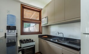 A compact kitchen with a water dispenser, a stove, a microwave, and a sink. - Apart in Condo w/ Pool 150 m From Village Cvb0112 (Maraú)