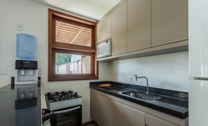 Cozinha compacta com um bebedouro, fogão, micro-ondas e pia.