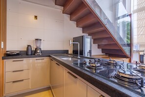 Eine moderne Küche mit eingebautem Gasherd, einer Kaffeemaschine und einem Mixer auf der Arbeitsfläche.