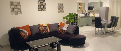 A living room with a sofa, coffee table, and a dining area with chairs and a table.