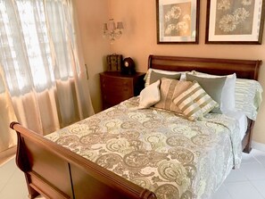 A bedroom with a wooden bed, patterned bedspread, and a nightstand with a lamp. - Fabulous 4-bedroom house with AC in beautiful Las Croabas (Las Croabas)
