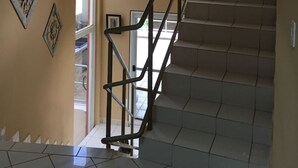 En trappa med ett metallräcke som leder upp till en liten plattform med en stor, inramad tavla.