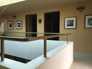 A balcony with a metal railing, a white wall with framed pictures, and a door leading to a dark interior. - Fabulous 4-bedroom house with AC in beautiful Las Croabas (Las Croabas)