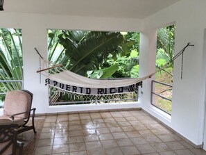 A room with a hammock, a chair, and a view of lush greenery. - Fabulous 4-bedroom house with AC in beautiful Las Croabas (Las Croabas)