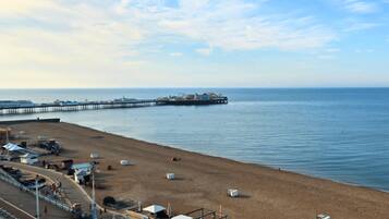 A beach with a pier extending into the water, a sandy shore, and a clear sky.