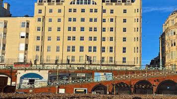 A multi-story building with a flat facade, numerous windows, and a brick base.