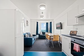 Une chambre d’hôtel compacte dotée d’une kitchenette, d’un coin repas, d’un canapé et offrant une vue sur la mer.