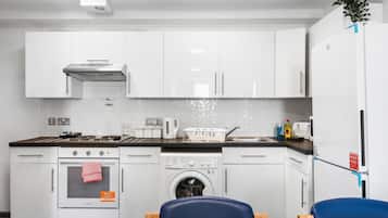 A modern kitchen with white cabinets, a built-in oven, a washing machine, and a refrigerator.
