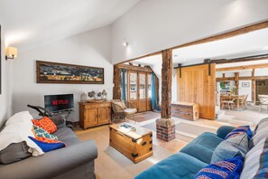Ein Wohnzimmer mit grauem Sofa, einer Holzkiste und einem Fernseher, der 'NETFLIX' anzeigt.