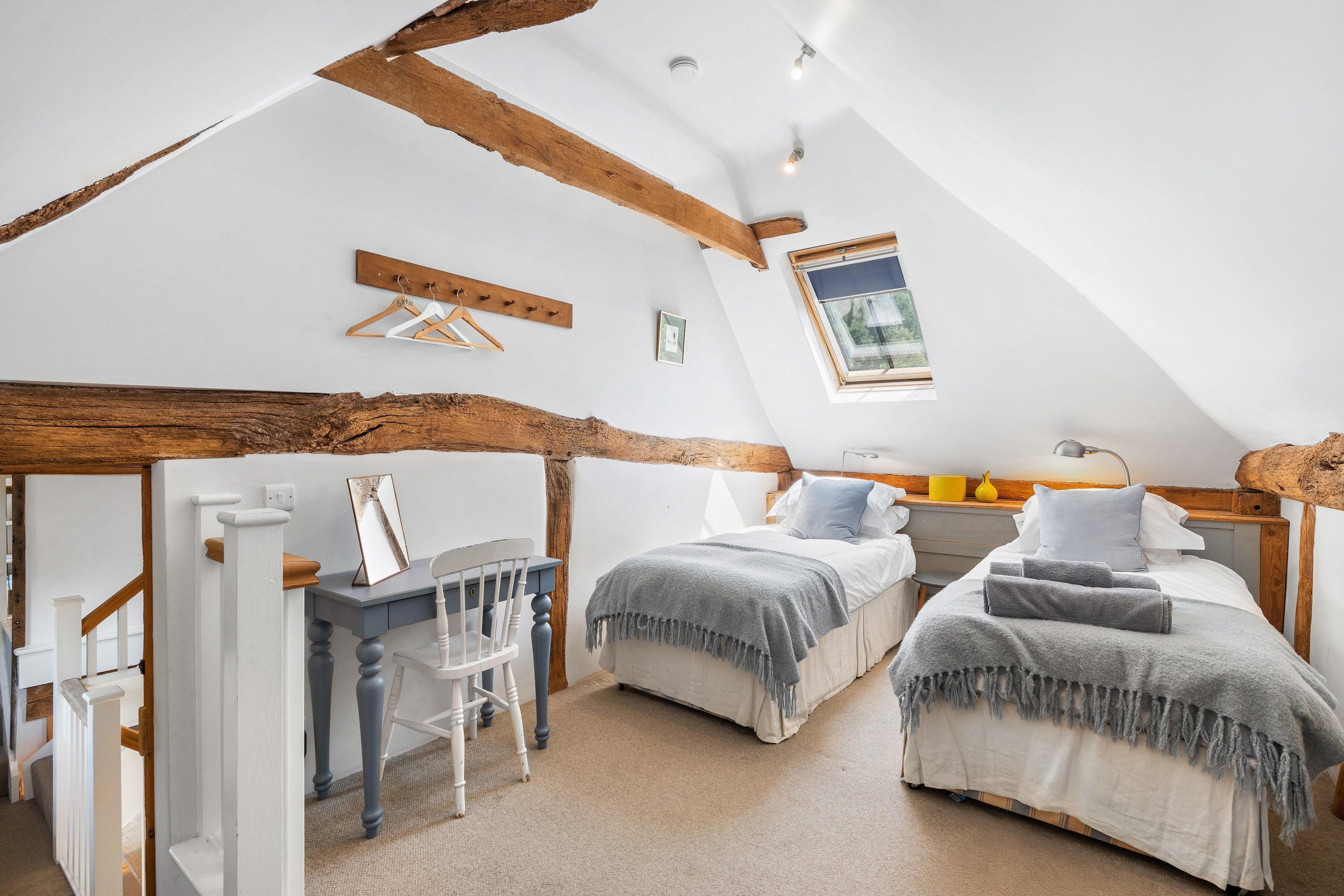 A bedroom with two beds, a desk, and a chair.