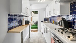 A modern kitchen with white cabinets, a stainless steel countertop, and blue-tiled backsplash. - Seaside Haven in Brighton (Brighton)