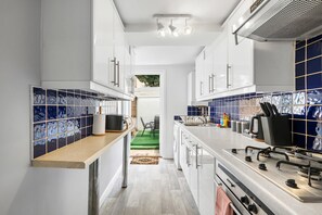 A modern kitchen with white cabinets, a stainless steel countertop, and blue-tiled backsplash. - Seaside Haven in Brighton (Brighton)