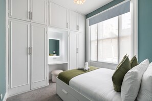A bedroom with a bed, a window, and built-in storage cabinets. - Seaside Haven in Brighton (Brighton)