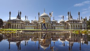 A large building with multiple domes and towers, a reflective water surface in front, and a person walking. - Seaside Haven in Brighton (Brighton)