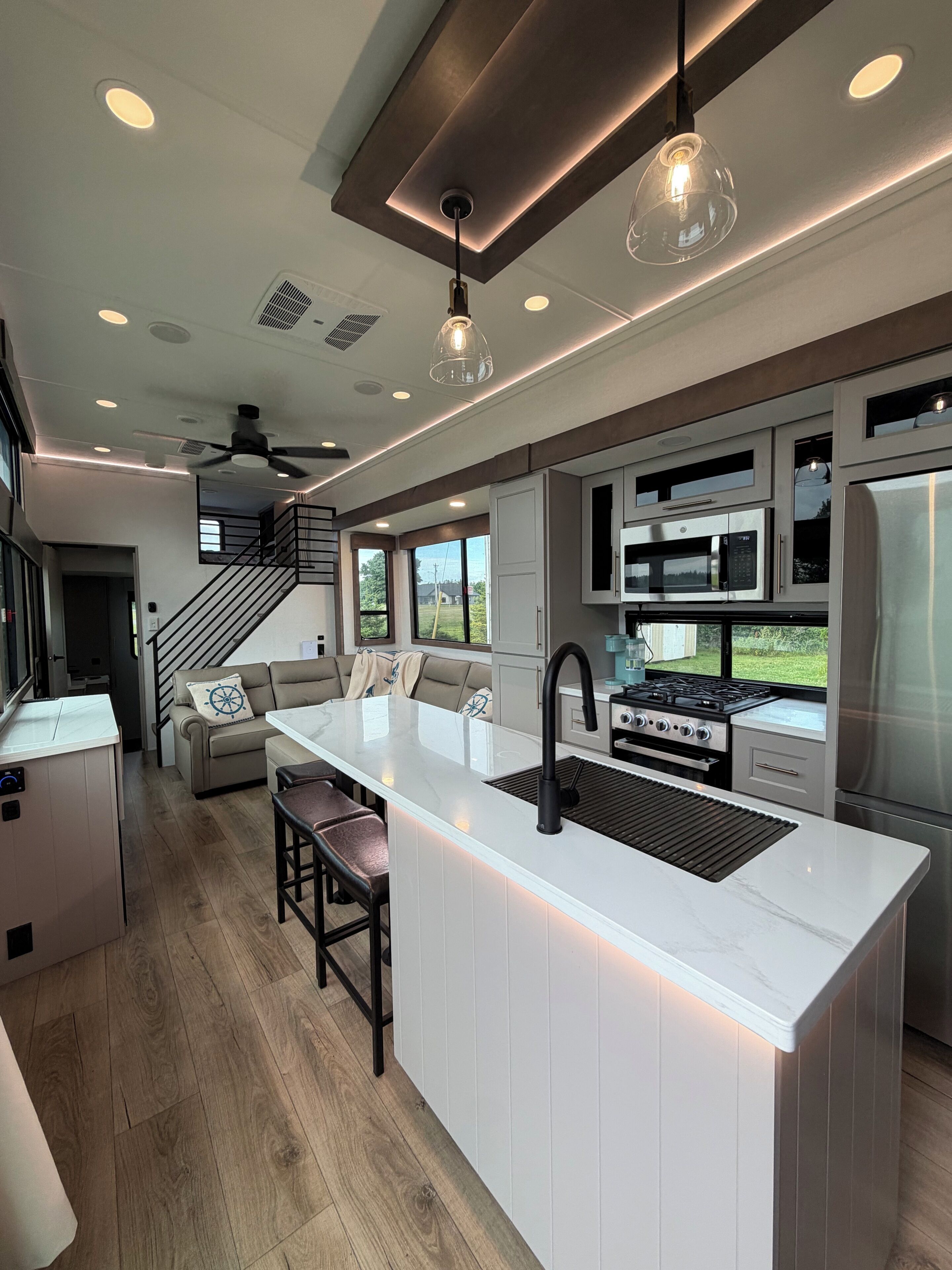 A modern kitchen with a central island, stainless steel appliances, and pendant lighting.