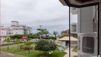 A balcony with a view of a residential area, including houses, a swimming pool, and a street.