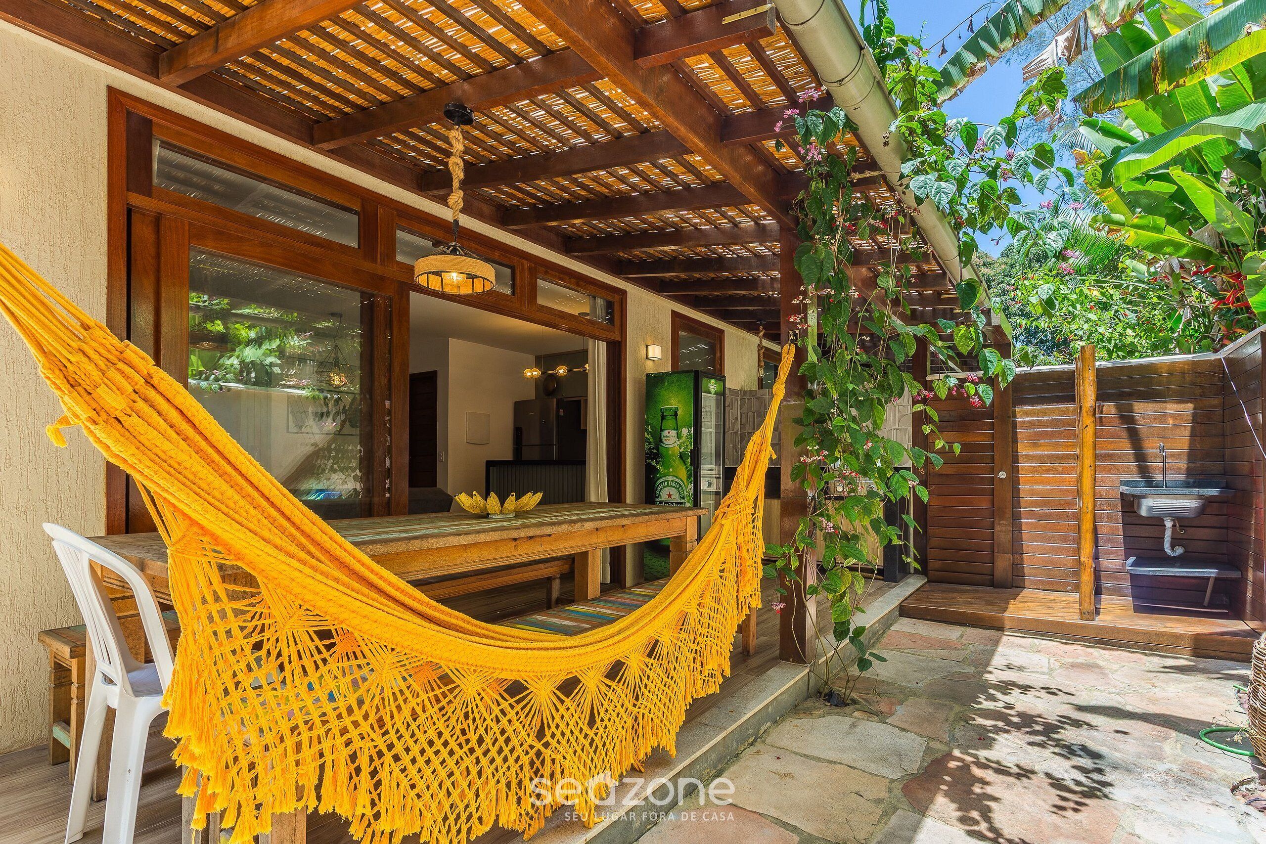 A hammock chair in a wooden outdoor seating area with a view of a lush garden and a stone pathway.