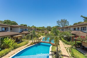 A swimming pool surrounded by a garden with a pergola and a gazebo. - Apt w/ Gourmet Area & BBQ in Marau Cvb0126 (Maraú)
