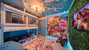 A room with a bunk bed, a floral carpet, a mural of a village, and a green wall. - Private Theater, Themed Rooms & Hot Tub (Davenport)