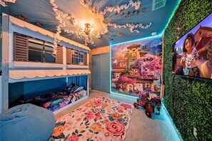 A room with a bunk bed, a floral carpet, a mural of a village, and a green wall. - Private Theater, Themed Rooms & Hot Tub (Davenport)