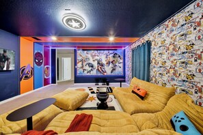 A room with a large wall mural, a sofa set, and a ceiling light fixture. - Private Theater, Themed Rooms & Hot Tub (Davenport)