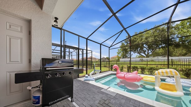 A barbecue grill, a swimming pool with inflatable toys, and a fenced outdoor area. - Private Theater, Themed Rooms & Hot Tub (Davenport)
